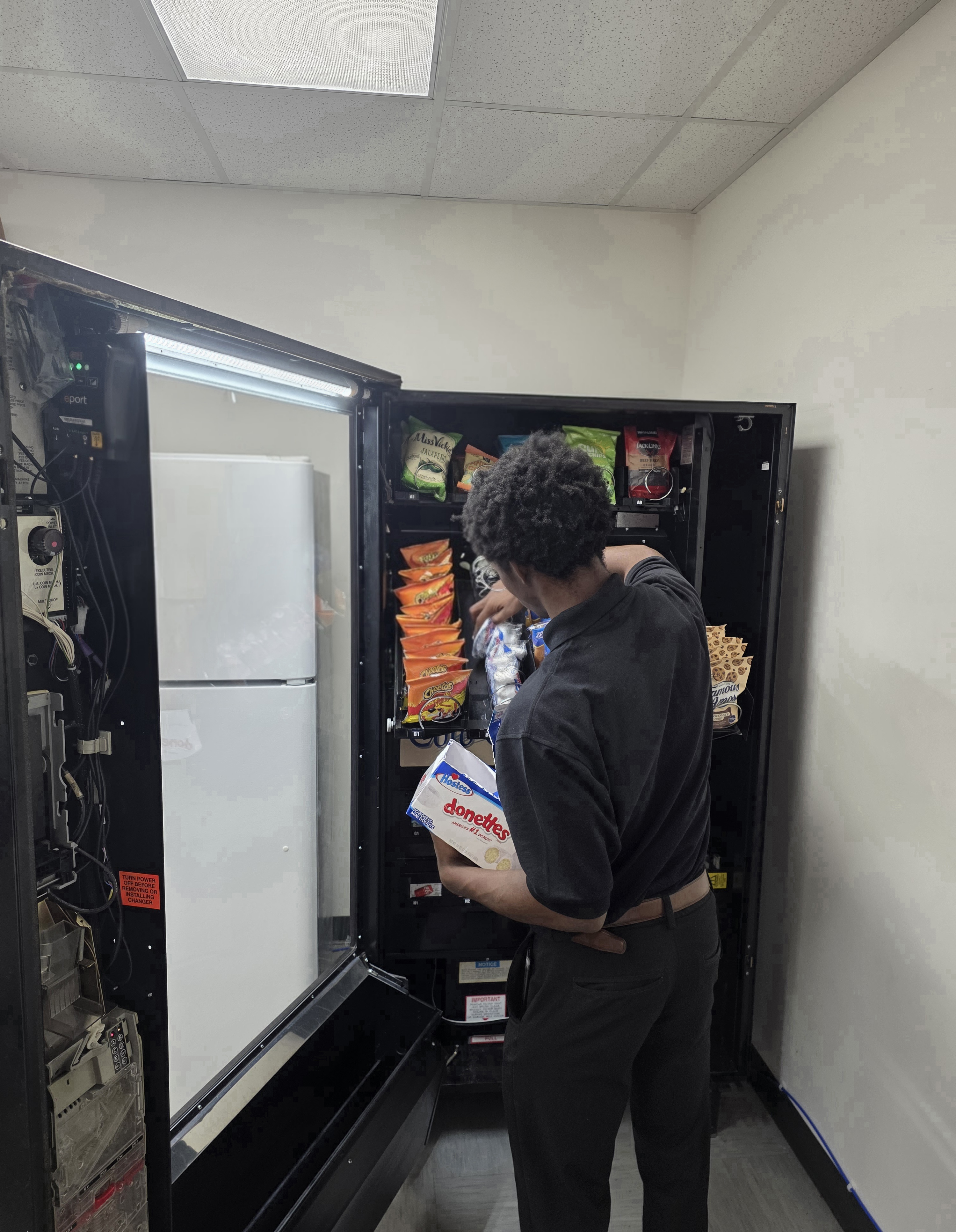 A man stocking a modern vending machine with snacks
